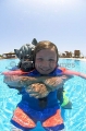 Young girl learning to scuba dive in swimming pool with instructor wearing joke mask. Young girl learning to scuba dive in swimming pool with instructor wearing joke mask.