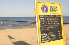Lifeguard beach report sign in patrolled and flagged area on tropical ocean beach with swimming enclosure using netting to provide protection for swimmers against potentially fatal jellyfish stings. Lifeguard beach report sign in patrolled and flagged area on tropical ocean beach with swimming enclosure using netting to provide protection for swimmers against potentially fatal jellyfish stings.