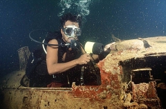 Diver in cockpit of Zero fighter aeroplane in forward hold on the Fujikawa Maru, Japanese WW II shipwreck.