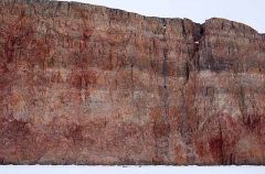 Skidoo and Kamotik or sled dwarfed while travelling across sea ice next to cliffs. Skidoo and Kamotik or sled dwarfed while travelling across sea ice next to cliffs.