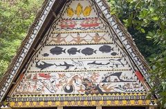 Traditional Bai meeting hall in Palau, Micronesia, with story board artwork on gables containing ocean themes including fish and sharks.