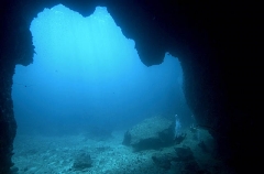 Divers at entrance of sea cavern. Divers at entrance of sea cavern.