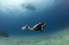 Scuba diver swimming over coral reef flat with dive boat at the surface. Scuba diver swimming over coral reef flat with dive boat at the surface.