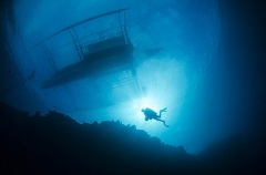 Diver on coral reef under Banca outrigger dive boat. Diver on coral reef under Banca outrigger dive boat.