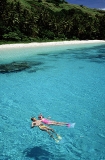 Young couple snorkel diving on coral reef with sandy beach and coconut trees. Young couple snorkel diving on coral reef with sandy beach and coconut trees.