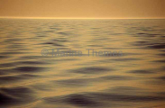 Gold and blue wave patterns with sea mist at sunset. Gold and blue wave patterns with sea mist at sunset.