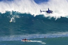 A helicopter filming a tow-in surfer at Peahi (Jaws)